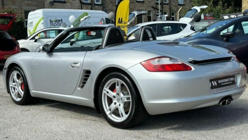 a silver sports car is parked in front of a smart repair van