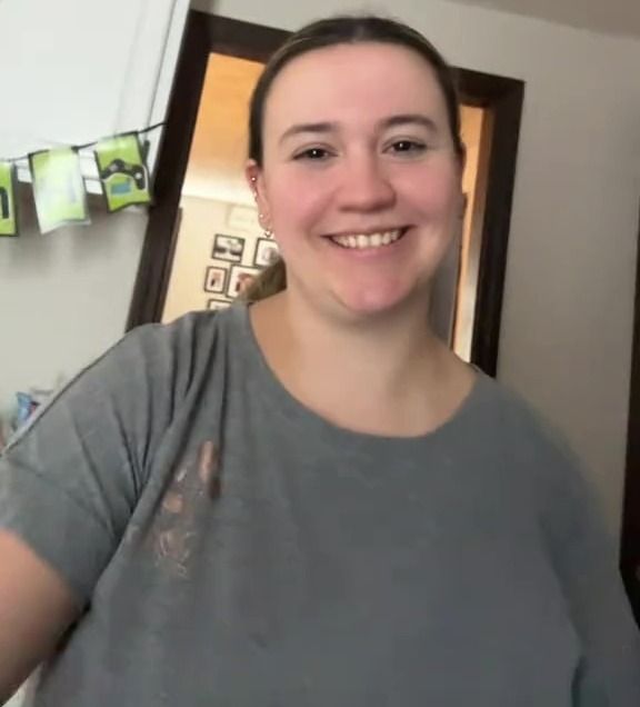 a woman is smiling and taking a selfie in a kitchen .
