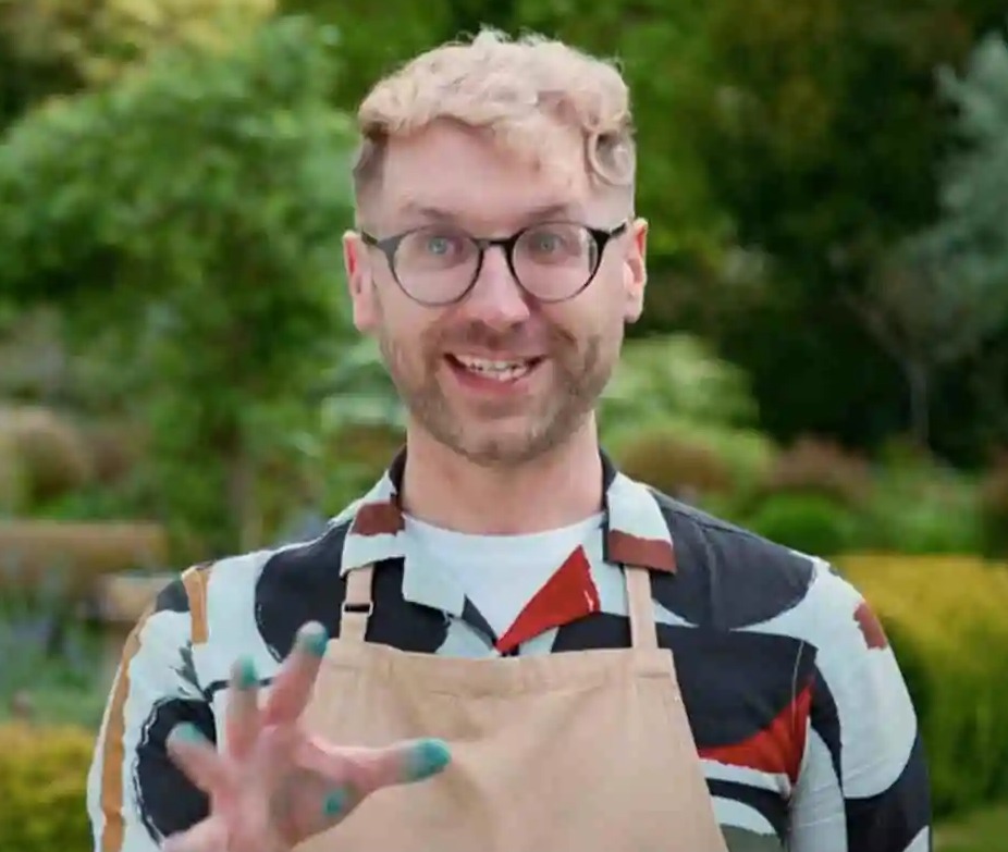 a man wearing glasses and an apron is standing in a garden