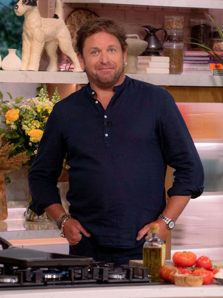 a man in a blue shirt stands in front of a stove with his hands on his hips