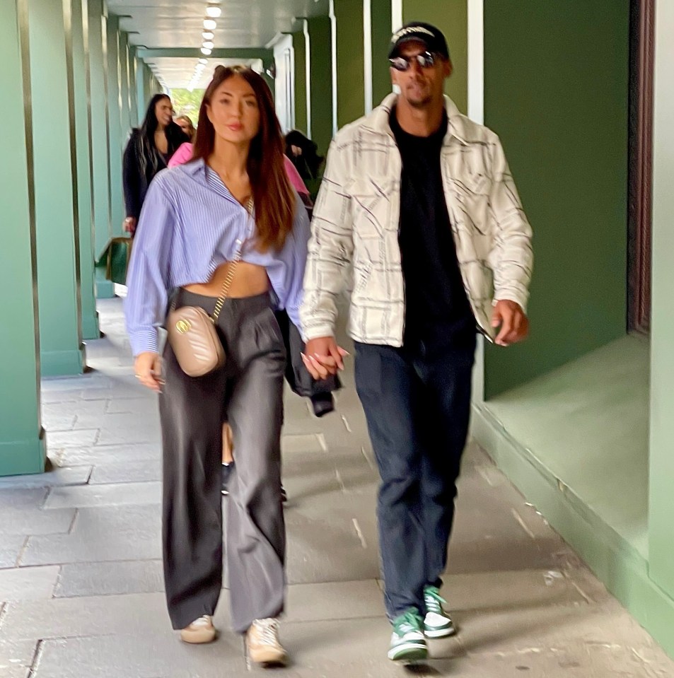 a man and a woman are walking down a sidewalk holding hands