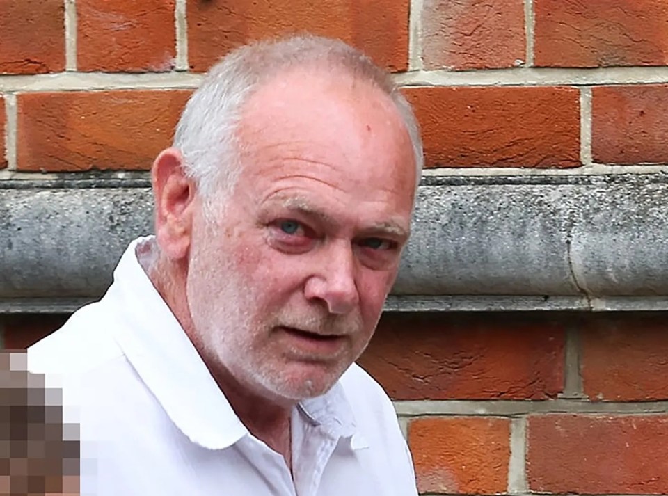 a man in a white shirt stands in front of a brick wall