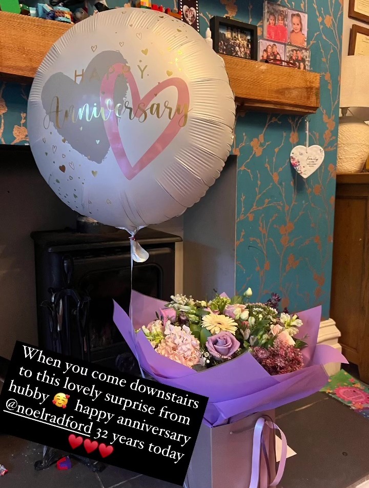 a happy anniversary balloon sits next to a bouquet of flowers