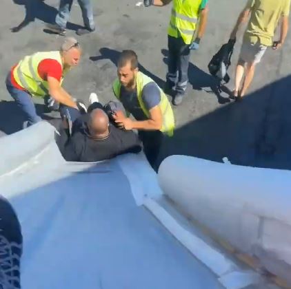 a group of men are standing around a man laying on the ground .