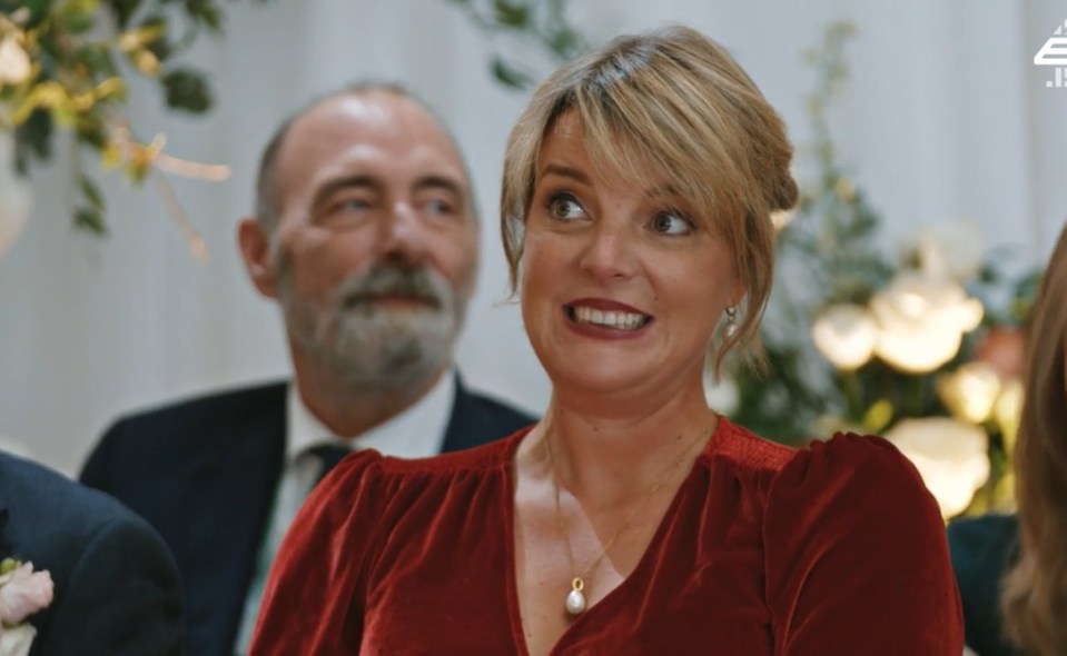 a woman in a red dress is smiling while a man in a suit looks on