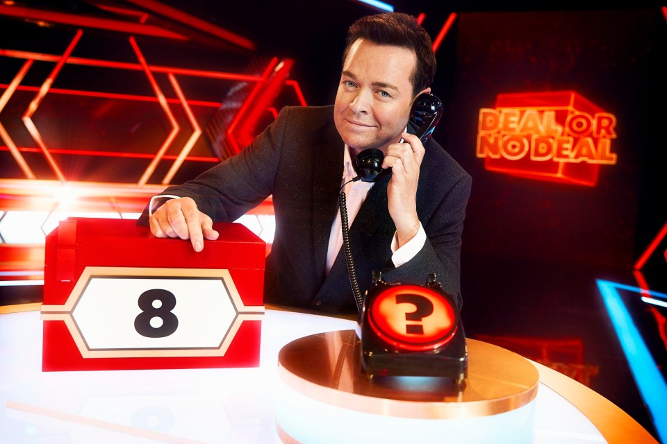 a man talking on a phone in front of a sign that says deal or no deal