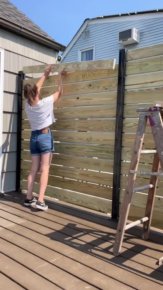 a woman is measuring a piece of wood on a deck