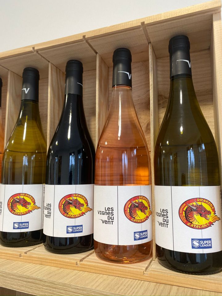 several bottles of wine are lined up on a wooden shelf