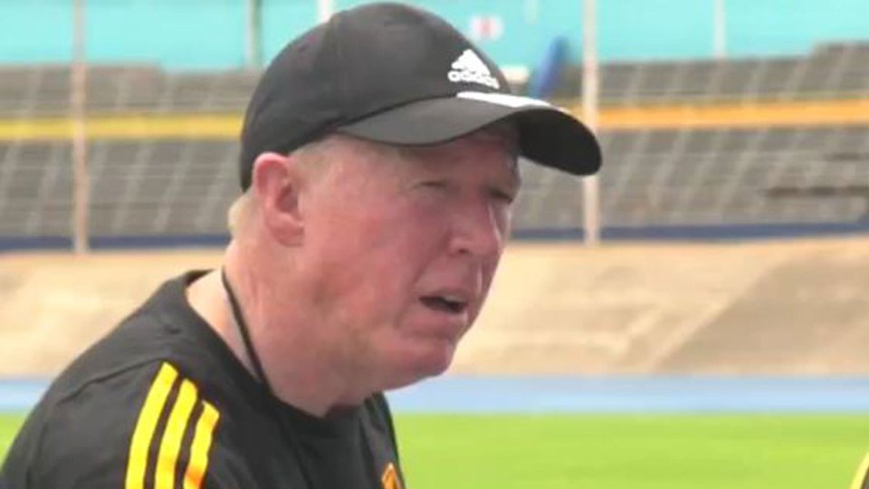 a man wearing a hat and a black shirt is talking on a field .