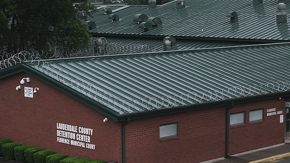 a brick building with a green roof that says lauderdale county detention center