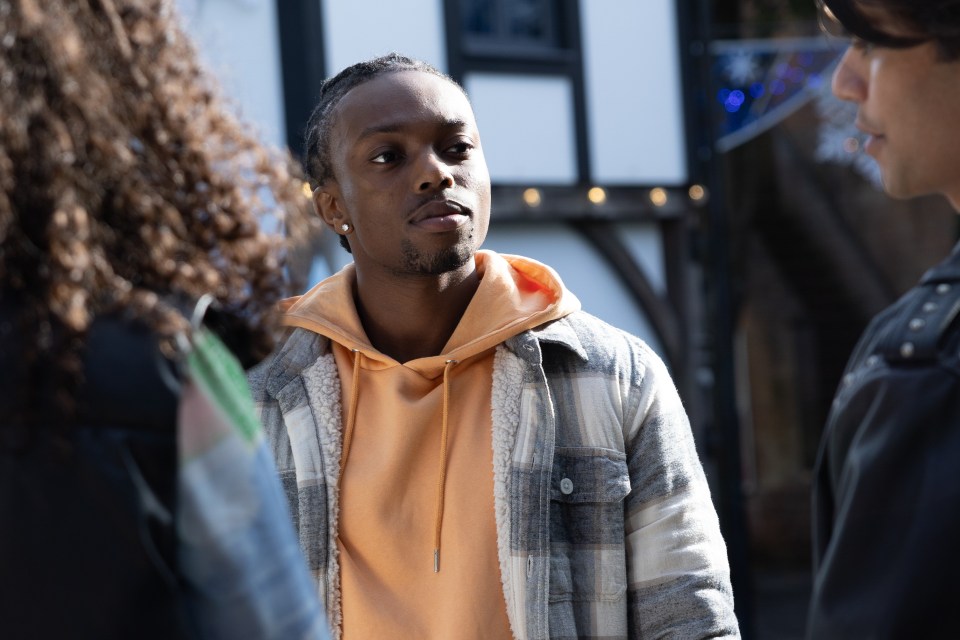 a man in an orange hoodie is talking to two other men
