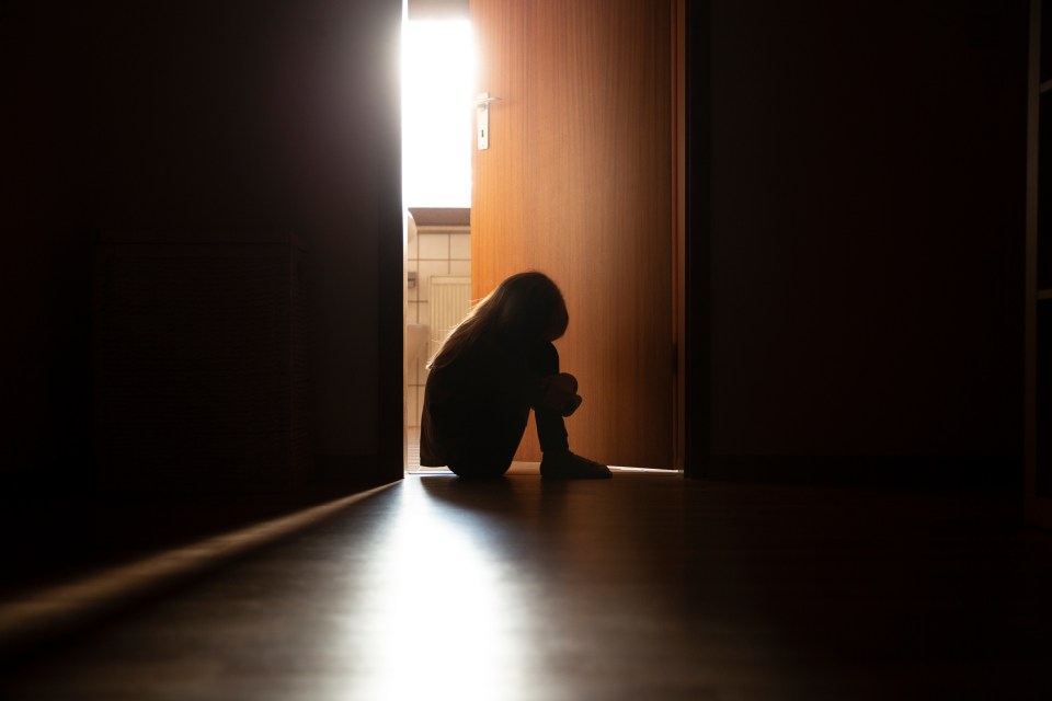 a silhouette of a person sitting in a doorway