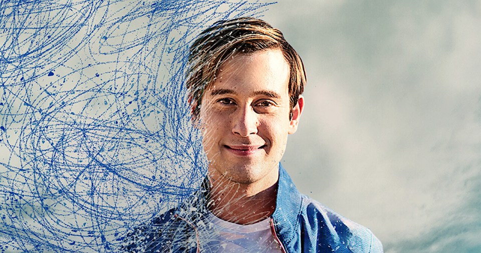 a man in a blue jacket is smiling in front of a blue background