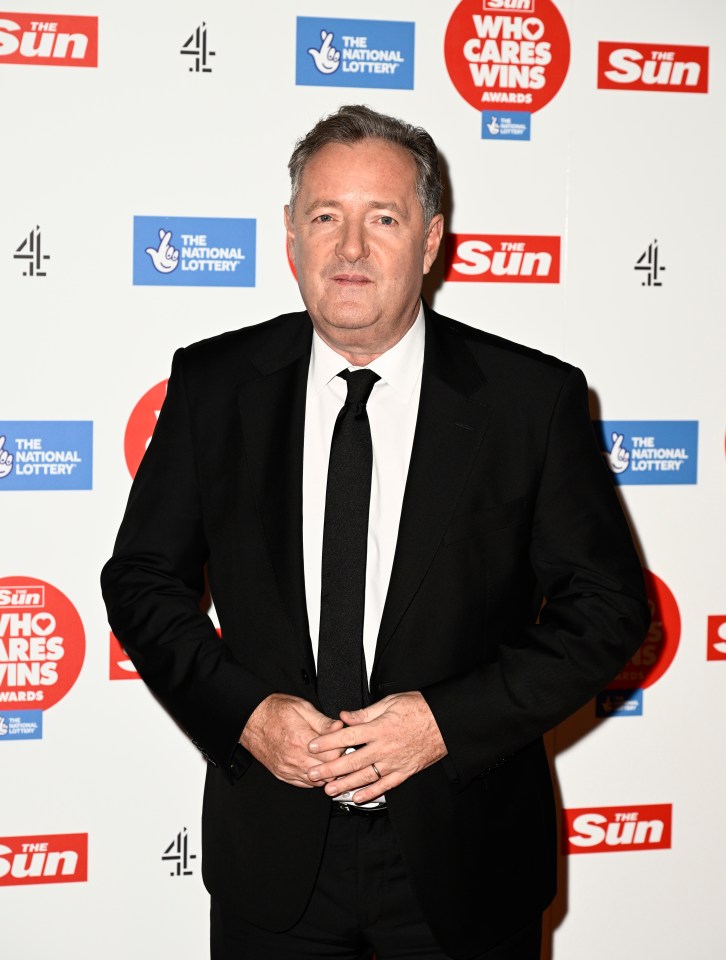 a man in a suit stands in front of a wall that says the sun