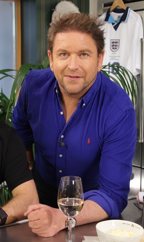 a man in a blue polo shirt holds a glass of wine
