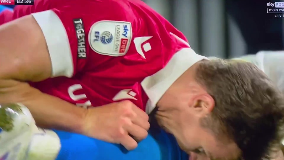 a soccer player is kissing another player 's leg on the field .