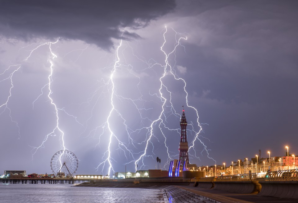 lightning strikes near a ferris wheel and a tower