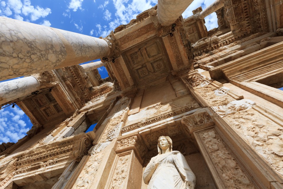a statue of a woman stands in front of a building with columns