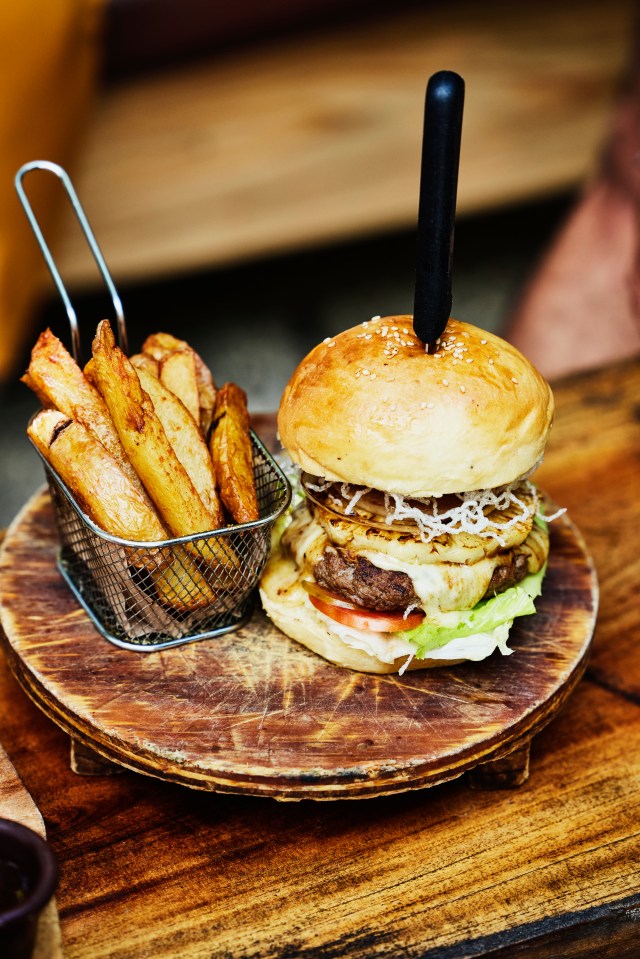 a hamburger and french fries on a wooden plate