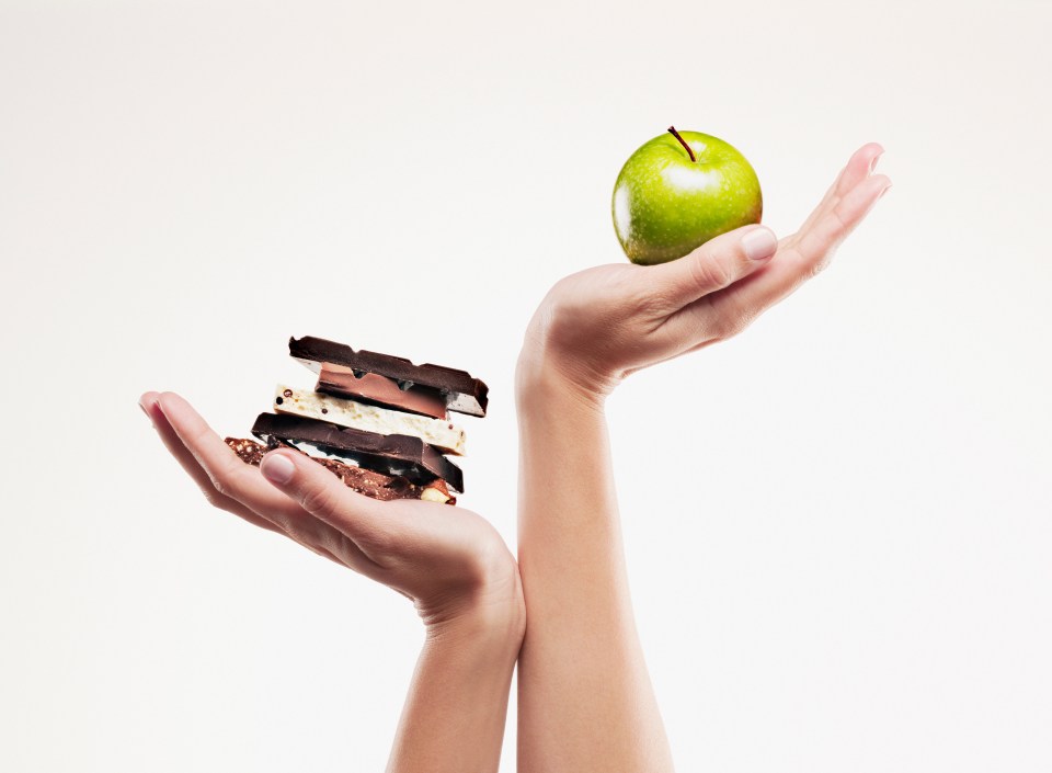 a person holding a green apple and a stack of chocolate bars