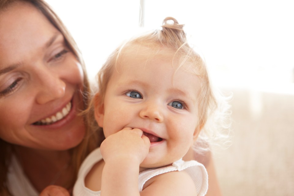 a woman is smiling while holding a baby in her arms
