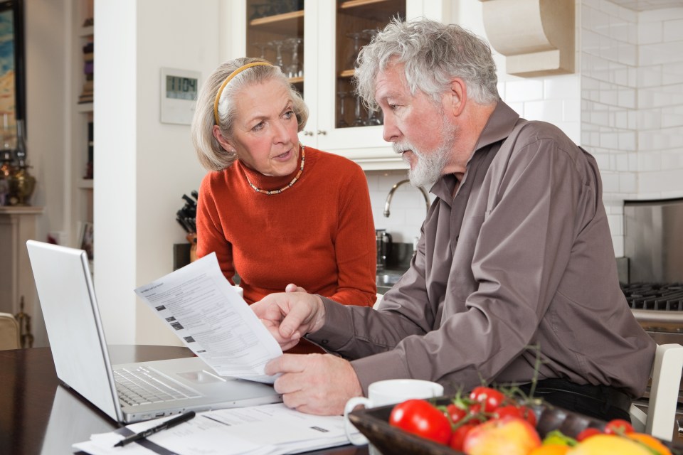 Senior couple reviewing finances on laptop.