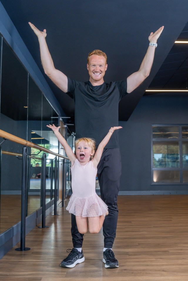 a man and a little girl are posing for a picture in a dance studio