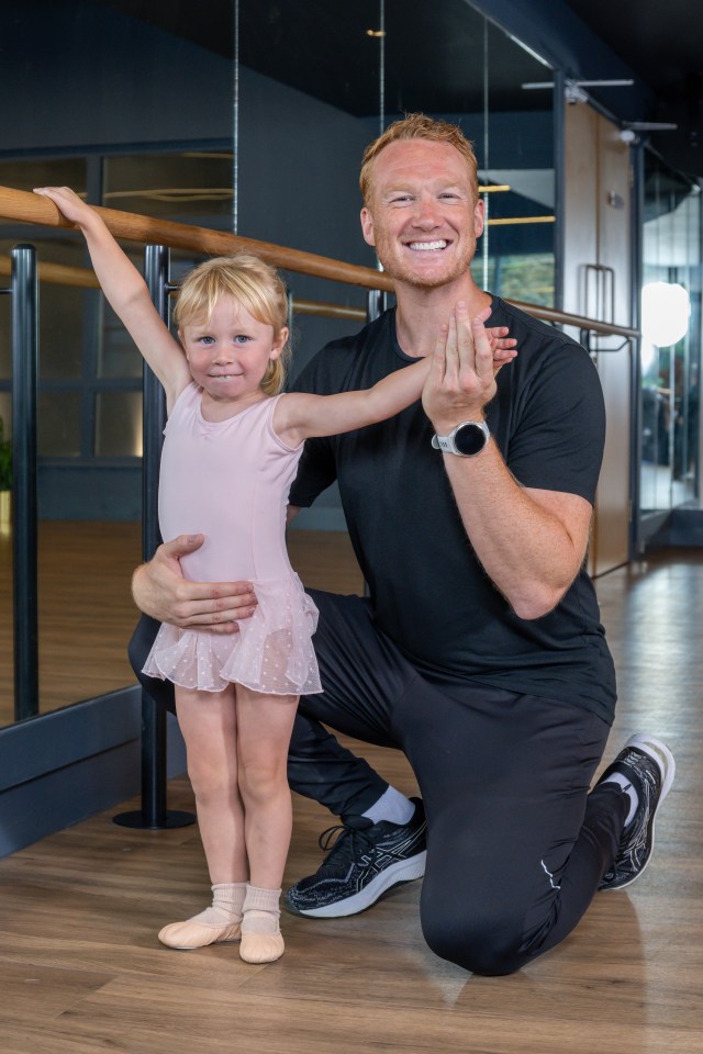 a man kneeling next to a little girl in a pink tutu