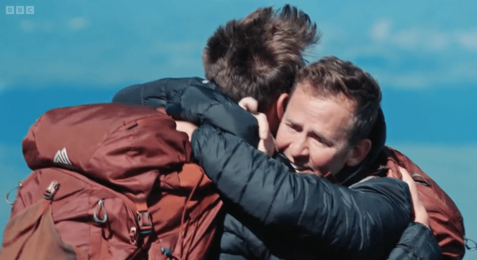two men hugging each other with a bbc logo in the background