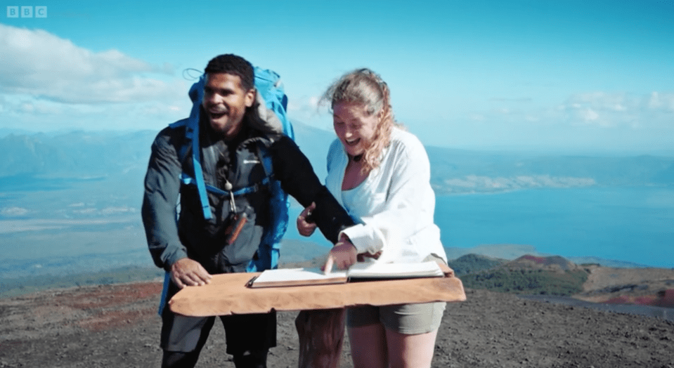 a man and a woman standing on top of a mountain with bbc written on the bottom