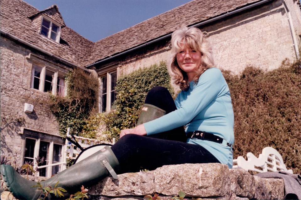 a woman sits on a stone wall in front of a house