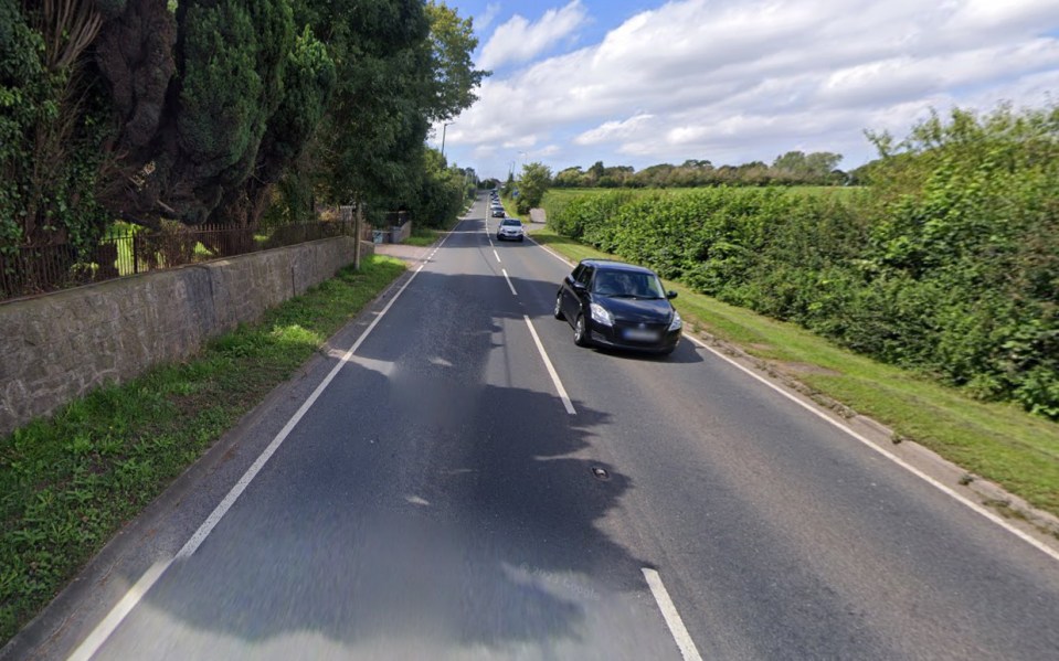 a black car is driving down a country road
