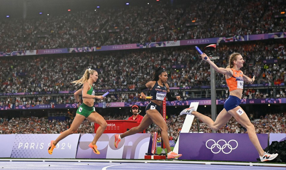 three female athletes are running in a relay race at the paris olympics