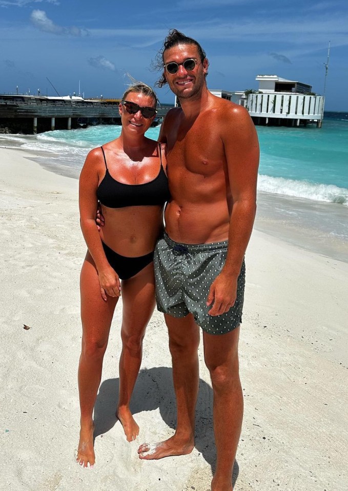 a man and a woman are posing for a picture on a beach