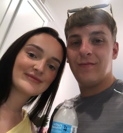 a man and a woman standing next to each other with a bottle of sparkling water