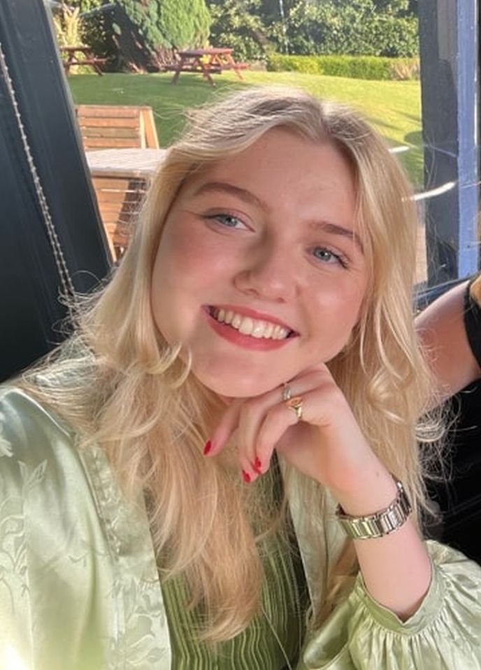 a woman wearing a watch and a ring smiles for the camera