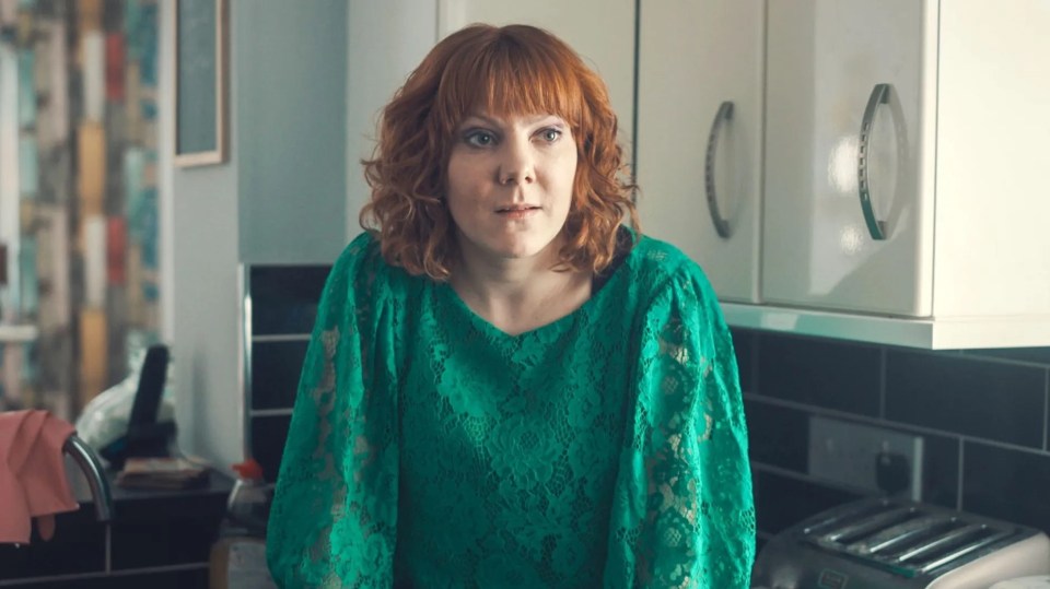 a woman in a green lace top sits in a kitchen
