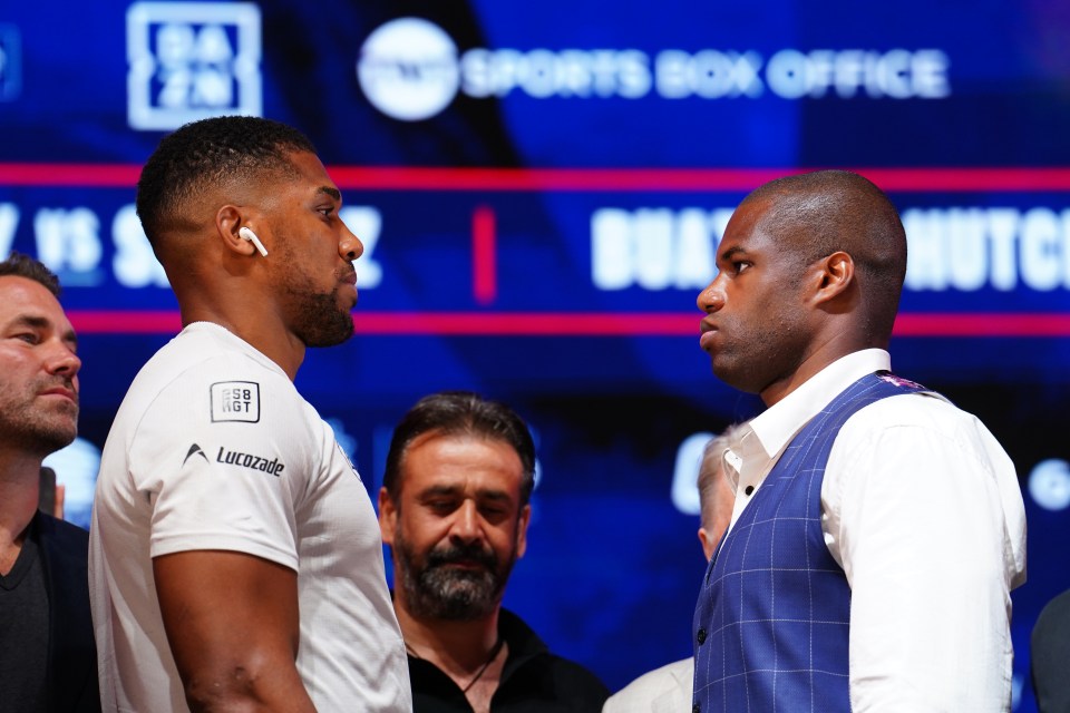 two men are facing each other in front of a sports box office sign
