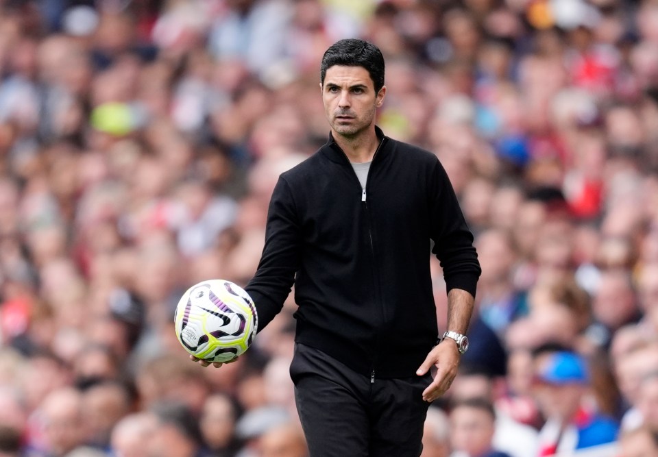 a man in a black jacket is holding a soccer ball