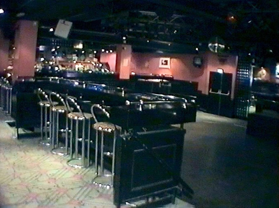 an empty bar with stools and a clock on the wall