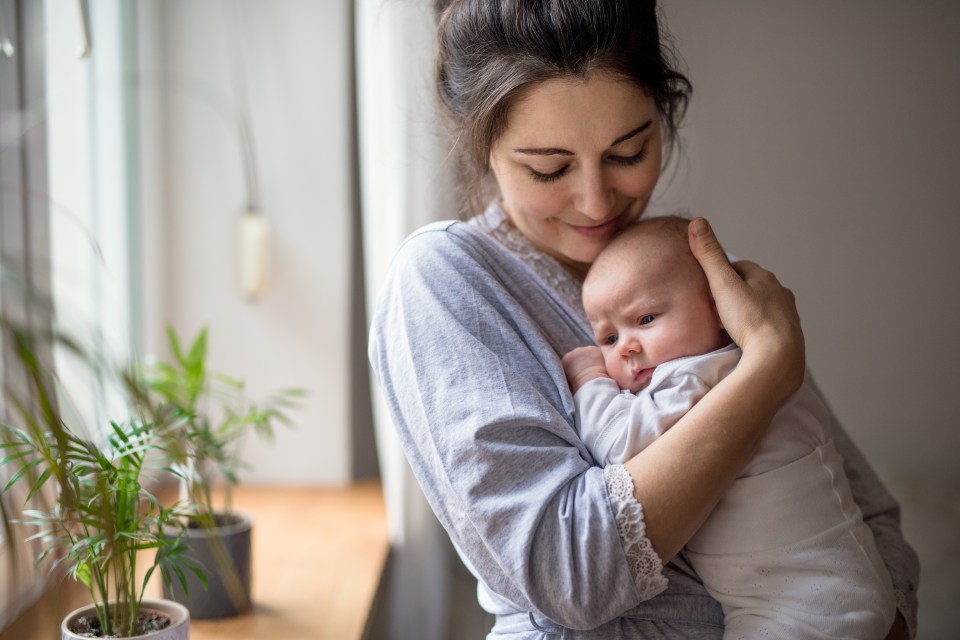 a woman is holding a baby in her arms in front of a window