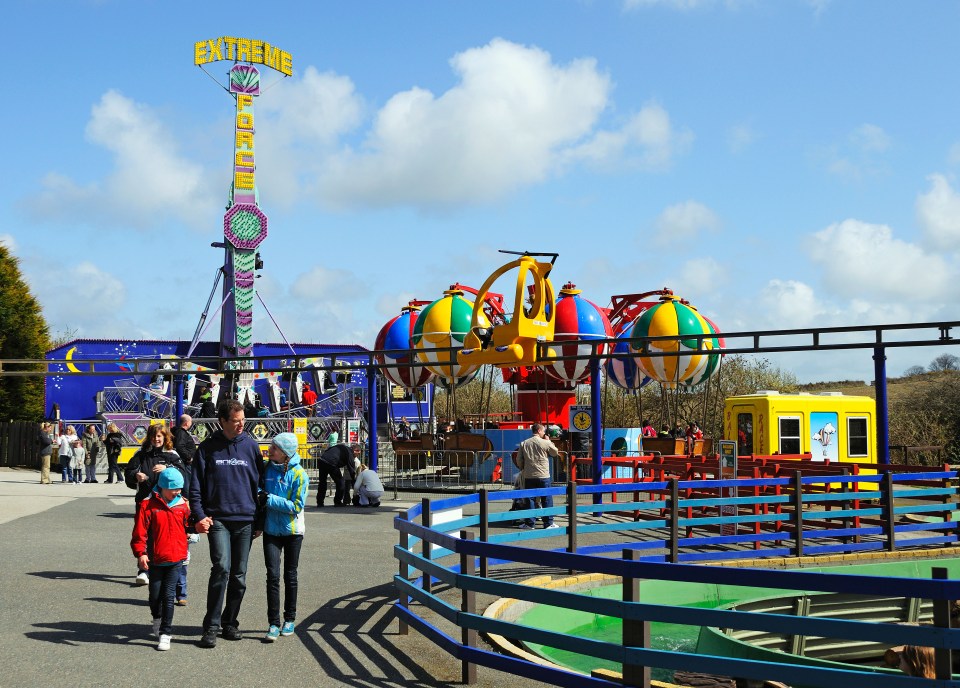 people walking in front of an extreme ride at an amusement park