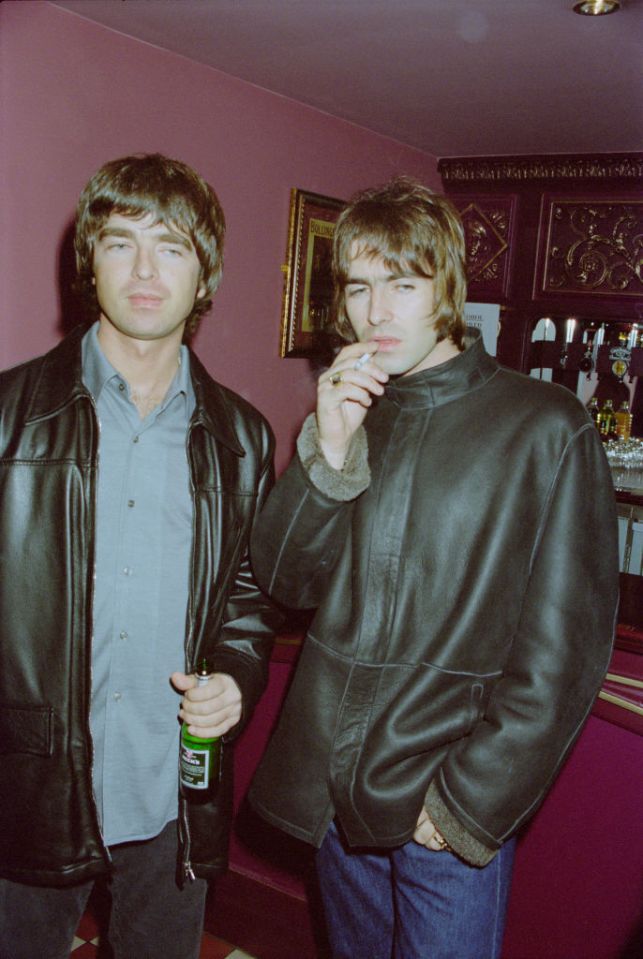 two men standing next to each other one holding a bottle of heineken beer