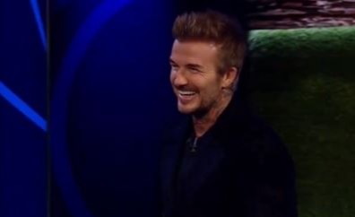 a man in a black jacket is smiling on a television show .