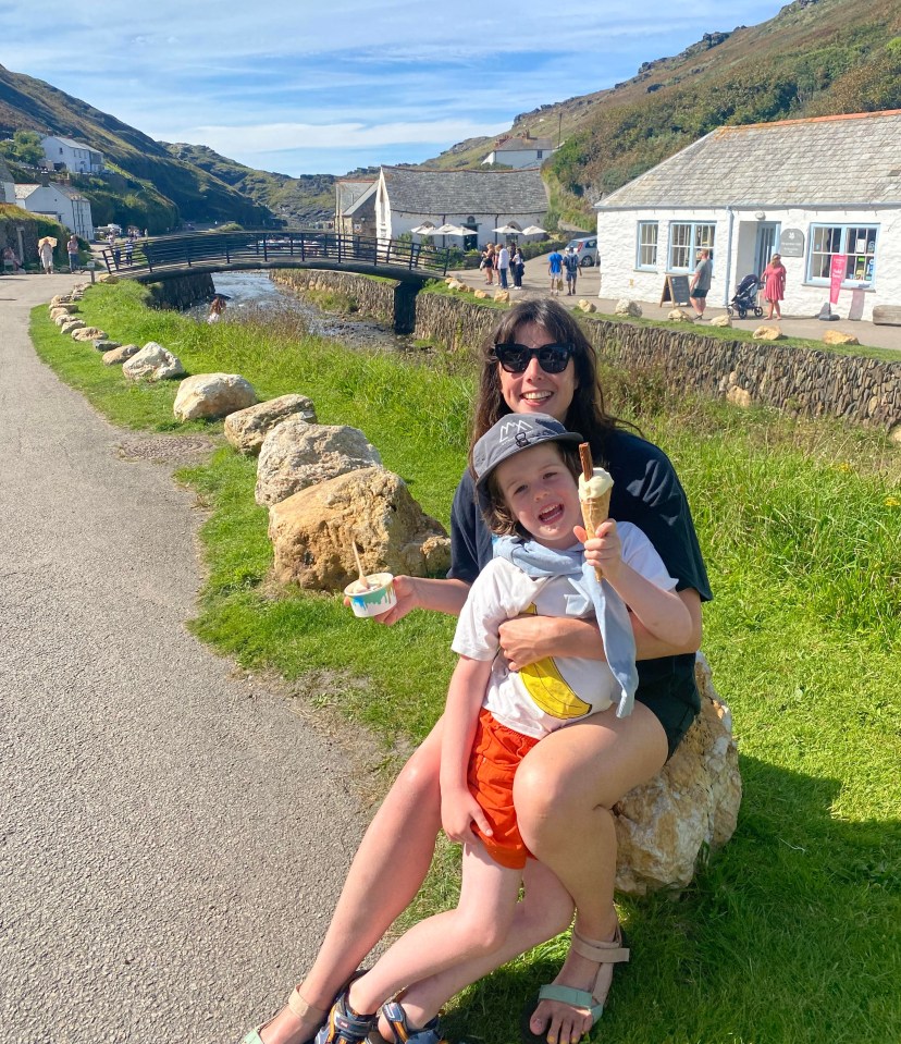 a woman sits on a rock with a child holding an ice cream cone