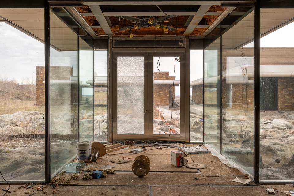 a bucket of white paint sits on the floor in front of a glass door