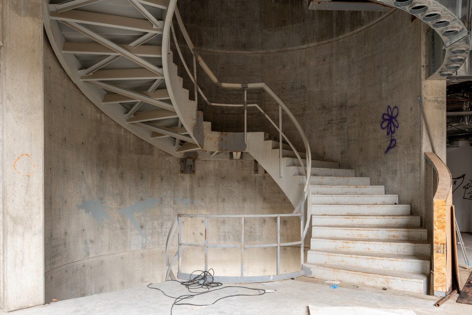 a spiral staircase in a building with graffiti on the wall
