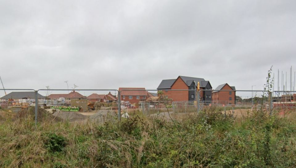 a fence surrounds a construction site with houses in the background