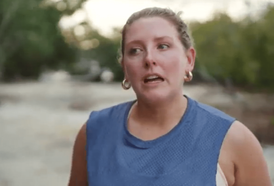 a woman in a blue tank top and hoop earrings is making a funny face .