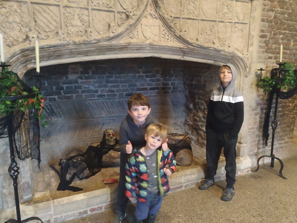 three young boys stand in front of a fireplace decorated for halloween